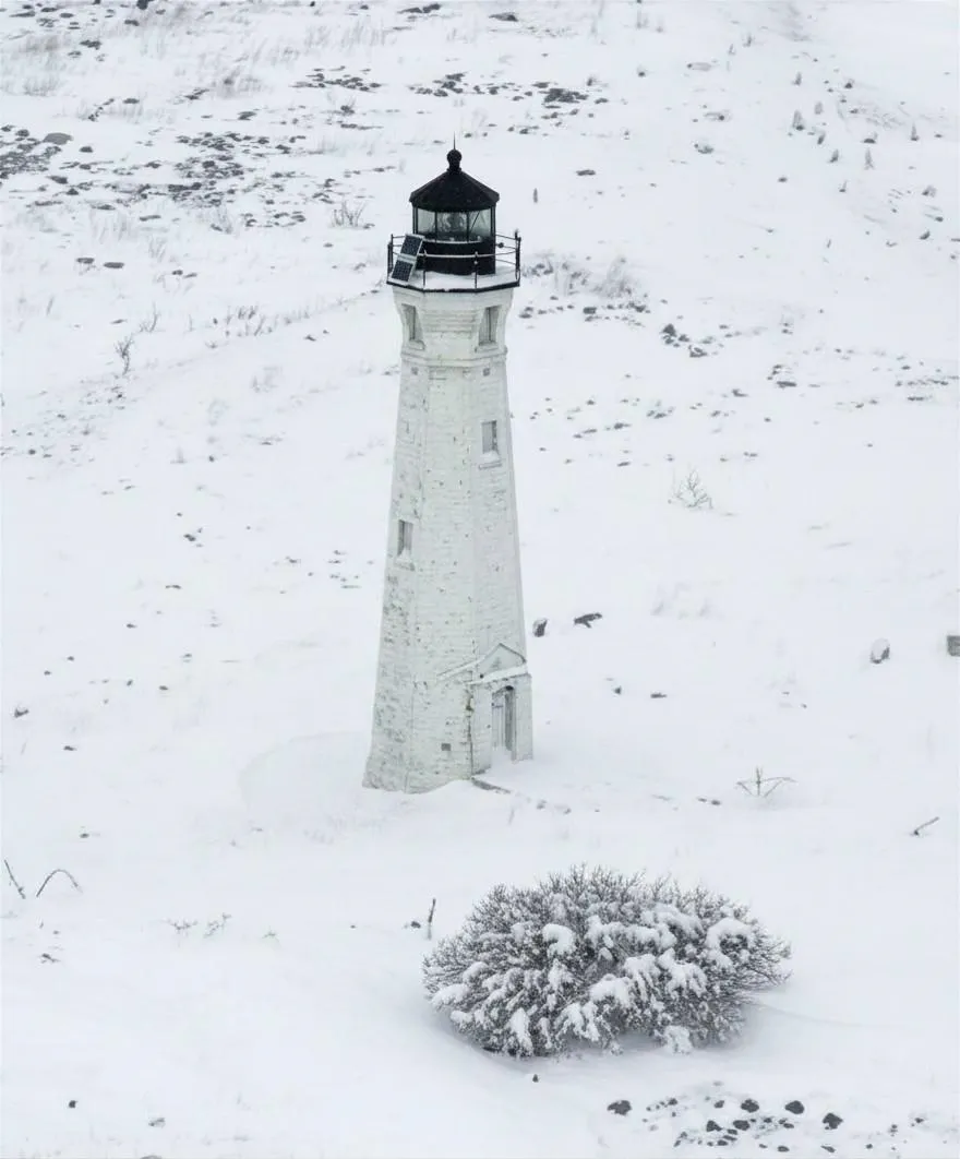 Skillagalee Lighthouse standing alone on a snow-covered island in winter.