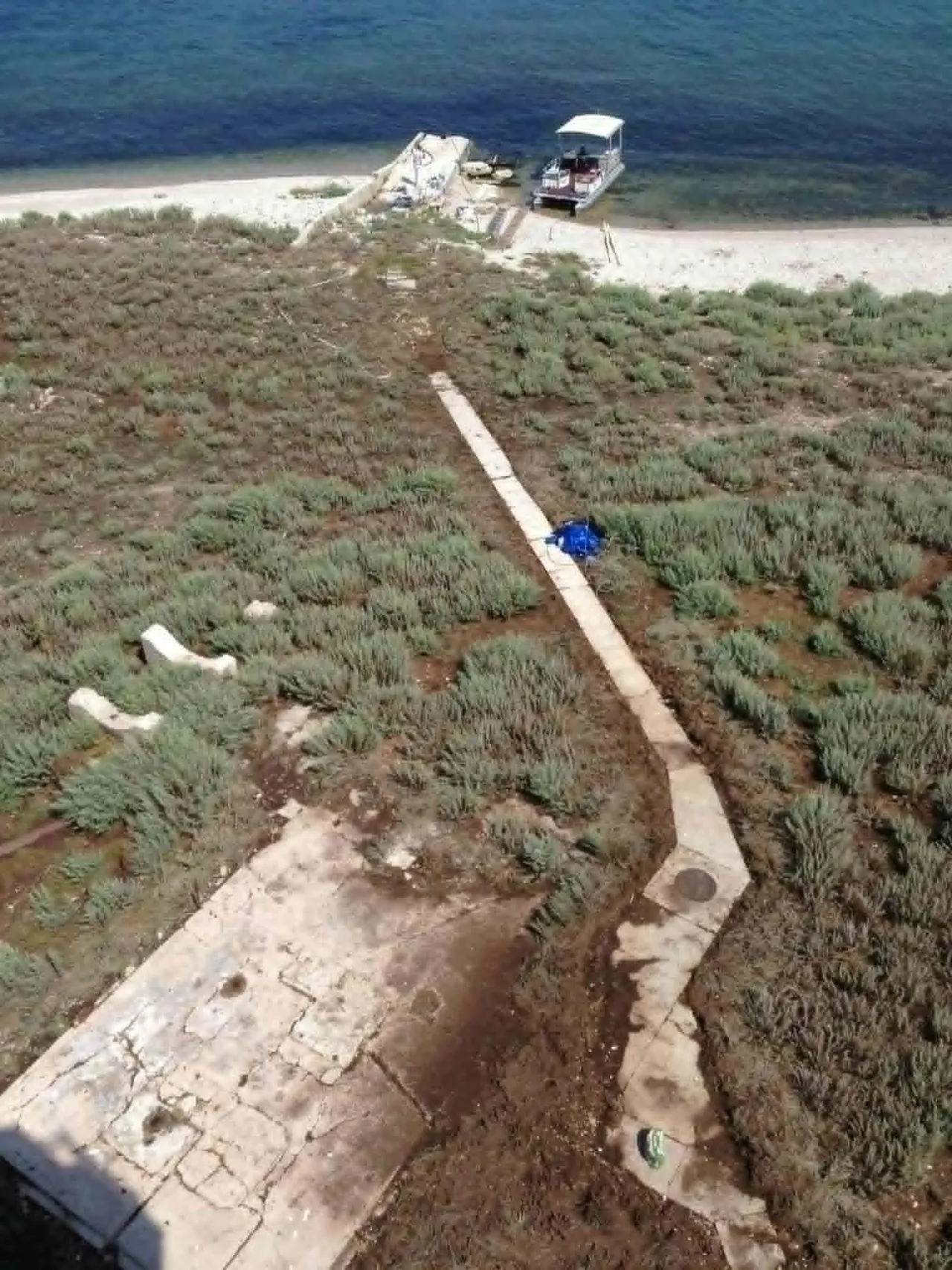 View down from the tower onto the gravel island with a boardwalk path and a boat at the landing.